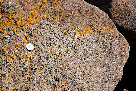 The 10p coin gives scale to the tiny holes in the dolerite caused by escaping gas at the time of its formation